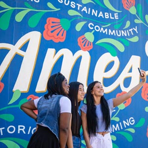 3 young ladies taking selfie in front of Ames mural