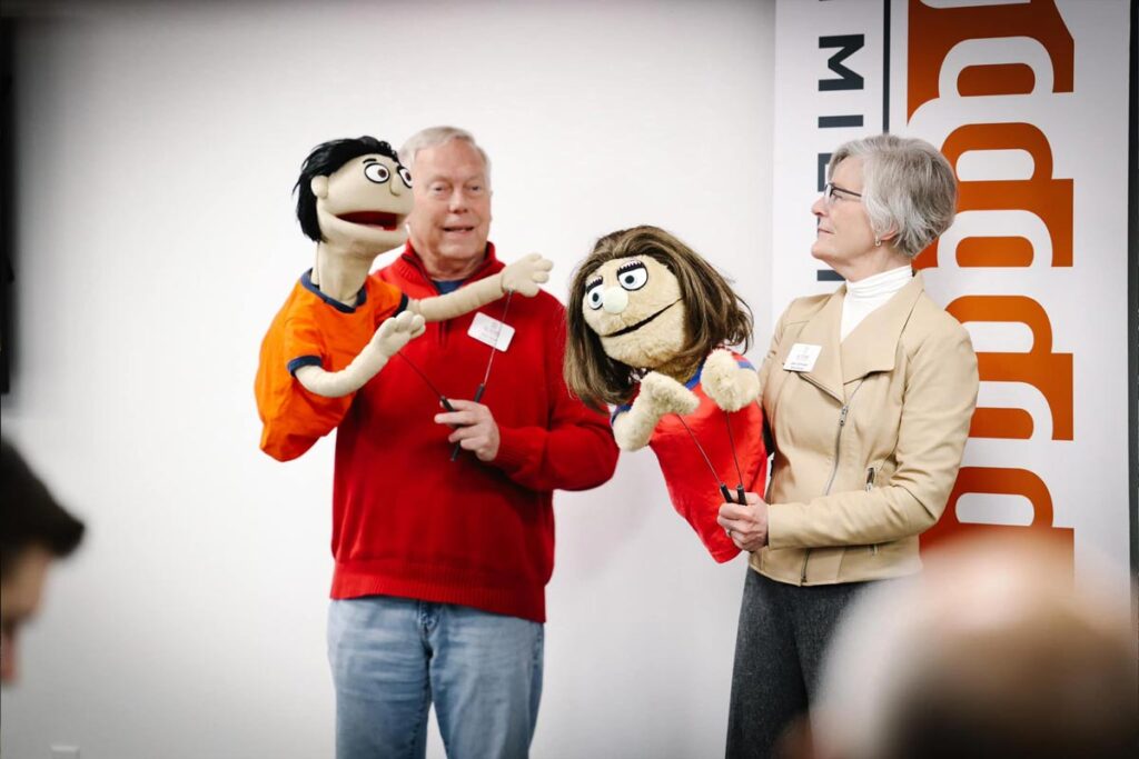 2 speakers with puppets at 1 Million Cups event