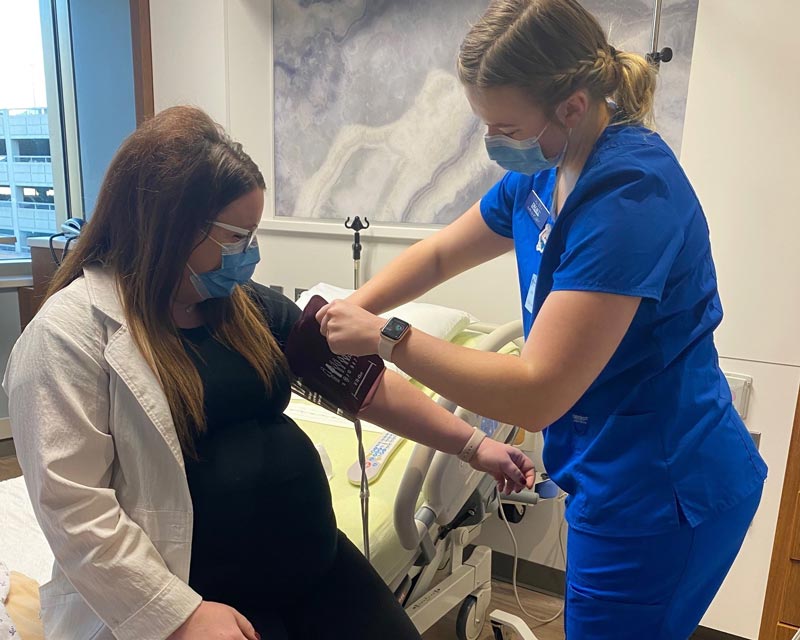 Nurse student practicing bloog pressure cuff on instructor